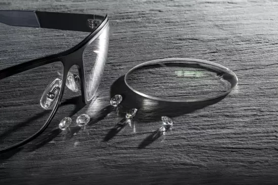 Black and white image of eyeglasses and lens on a table