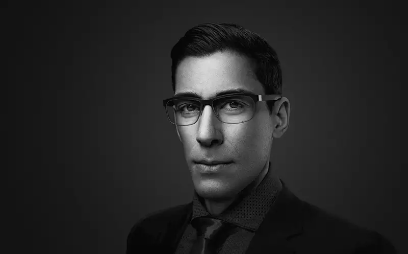 Black and white image of male wearing eyeglasses staring at the camera