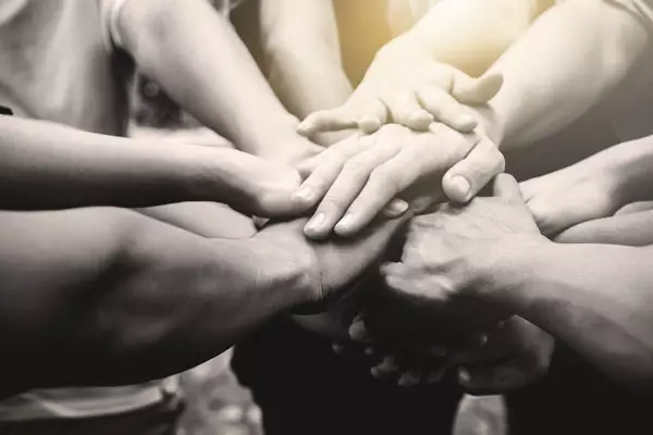 Group of hands in the centre of a circle of people