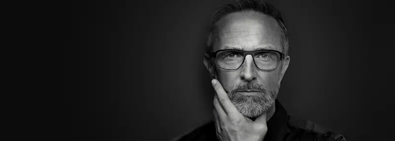 Black and white image of a male wearing eye glasses staring into the camera