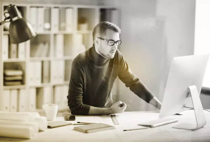 Male wearing eyeglasses working at a computer screen