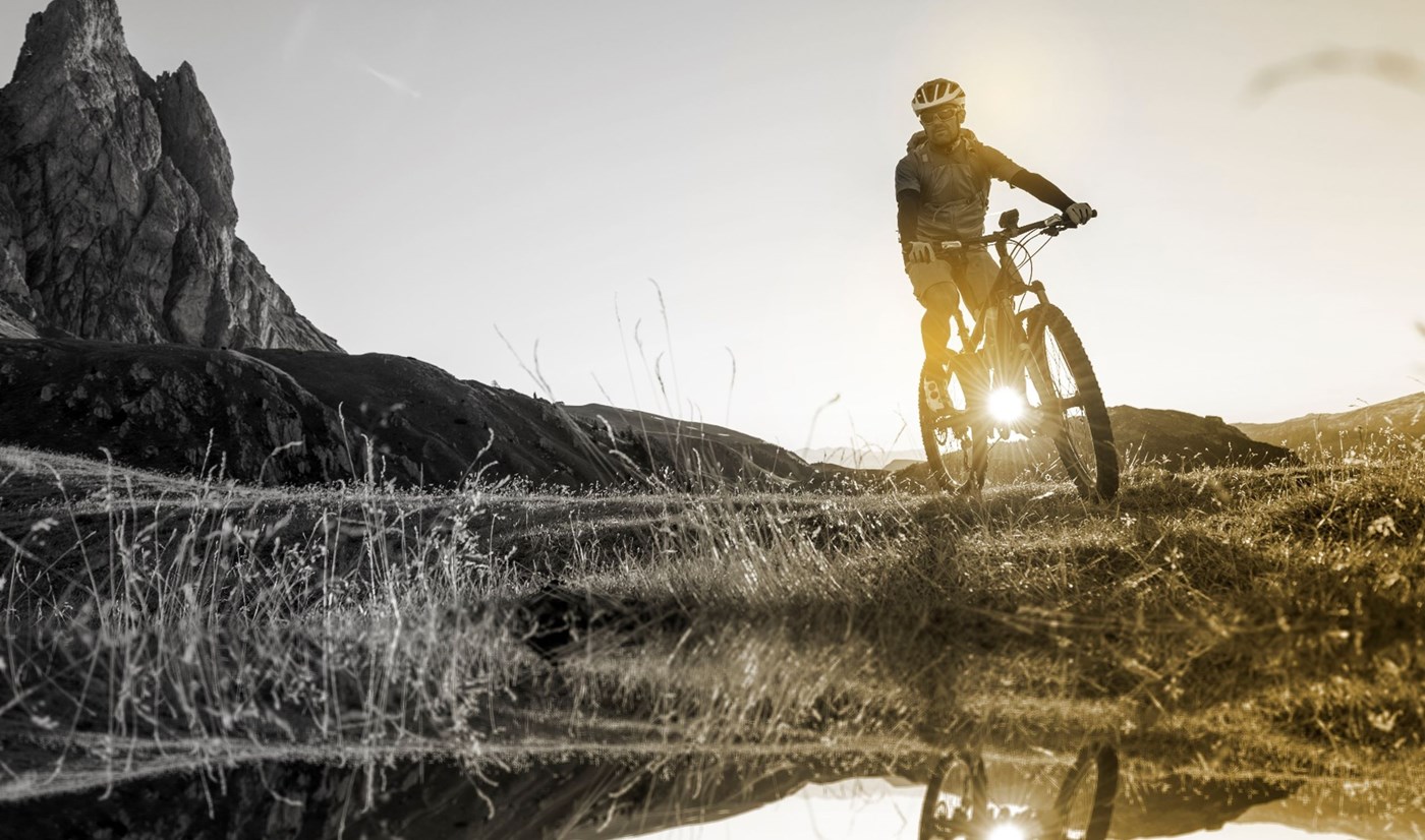 Male on a mountain bike with his reflection in a puddle