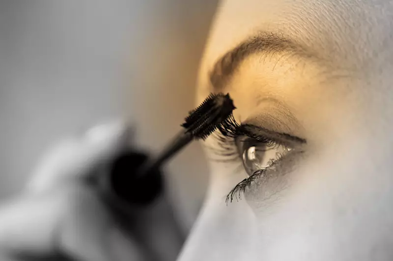 Female applying mascara on her left eye