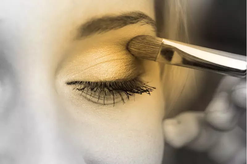 Female applying eyeshadow on her left eye