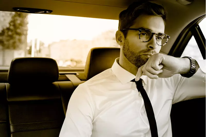 Male wearing eyeglasses in the back seat of a car