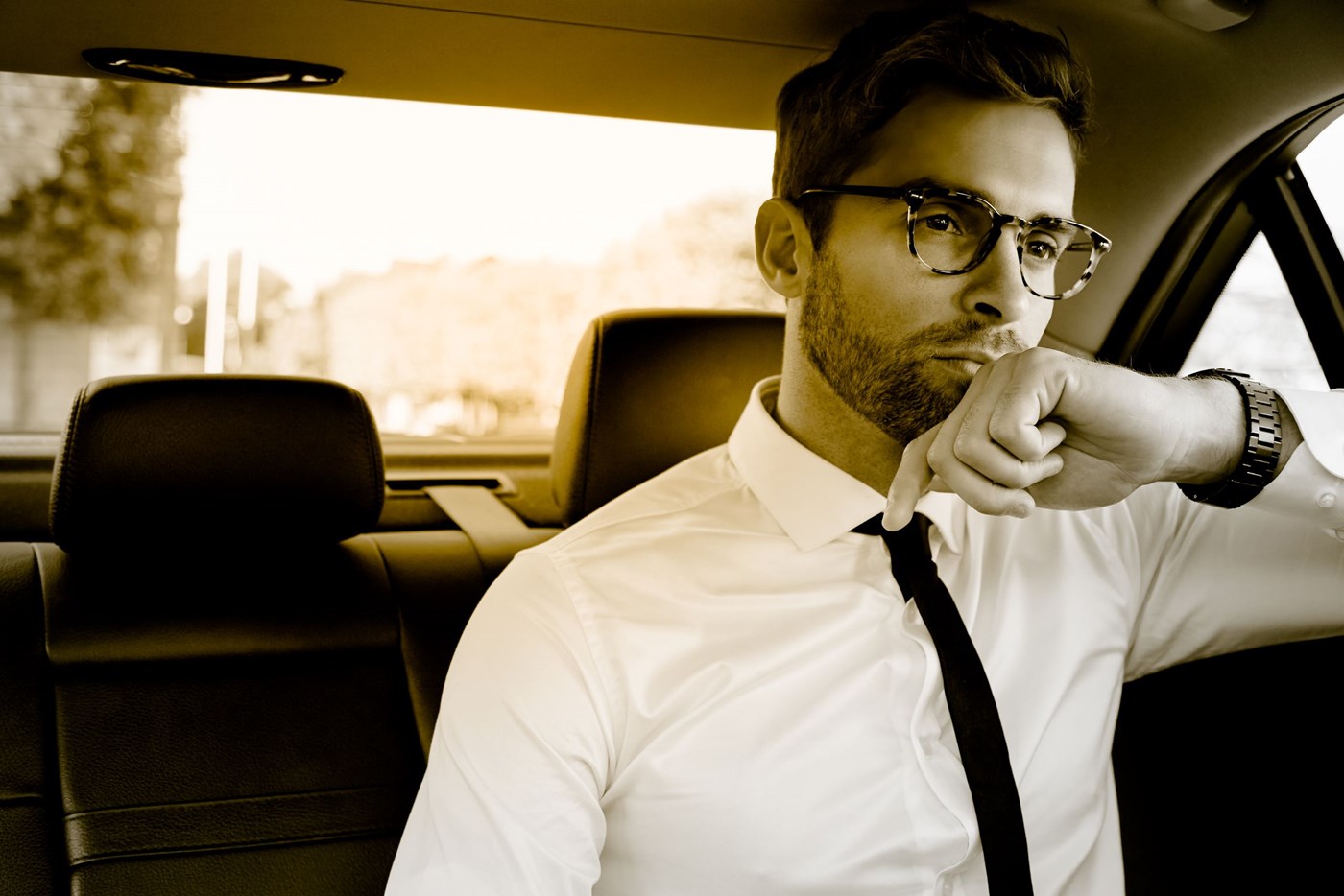 Male wearing eyeglasses in the back seat of a car