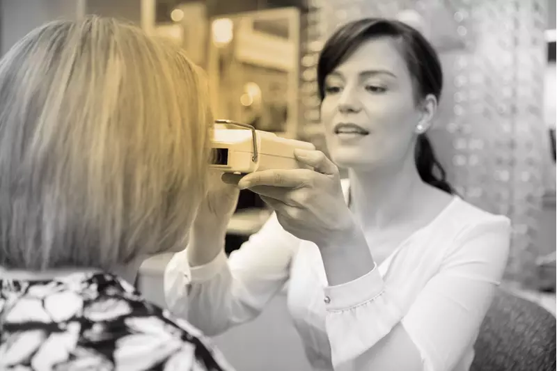 Female optician carrying out an eye examination on a female