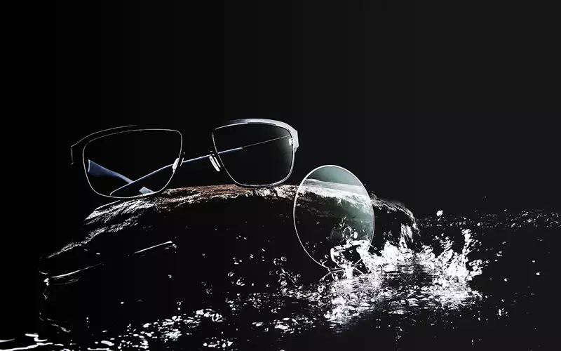 Eyeglasses and lens being splashed with water on a black background