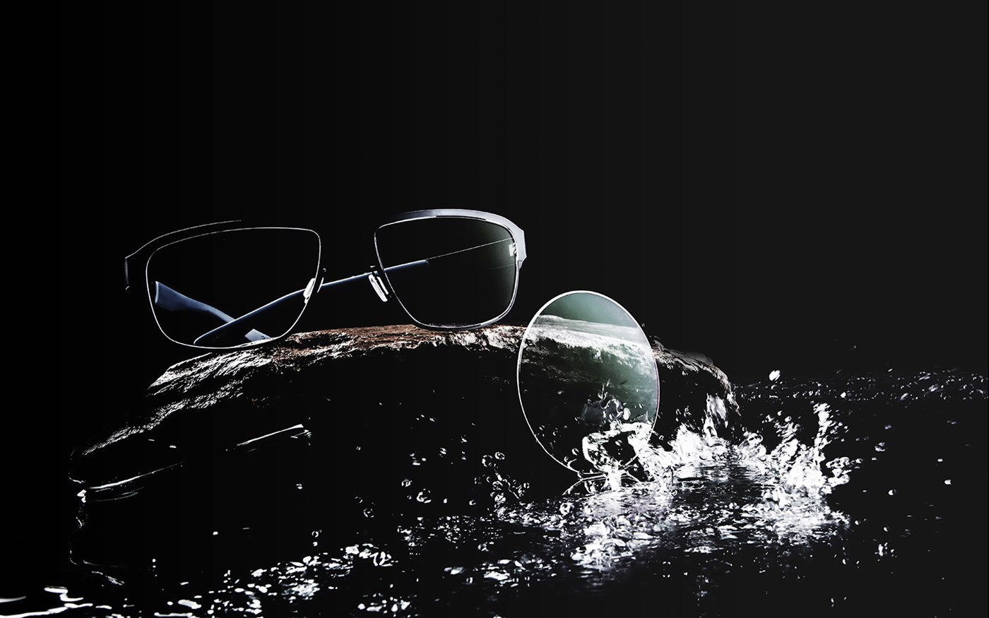 Eyeglasses and lens being splashed with water on a black background