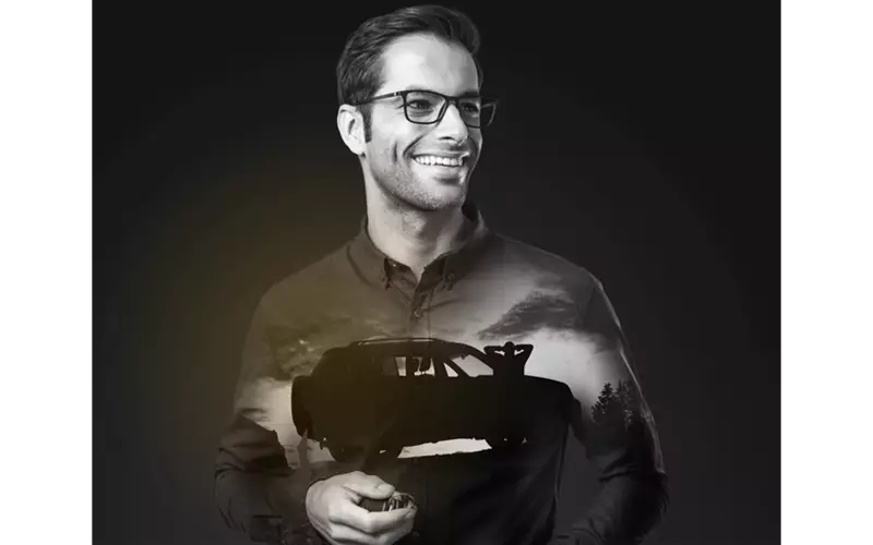 Male wearing eyeglasses smiling looking away from the camera with reflection of jeep on his tshirt