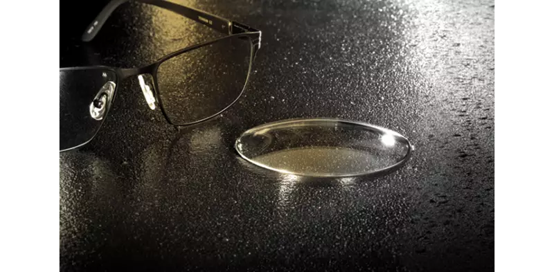 Lens sitting on table top beside a pair of eyeglasses