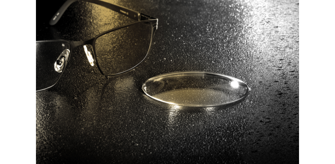Lens sitting on table top beside a pair of eyeglasses