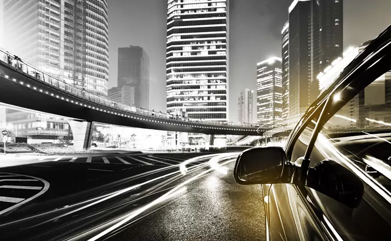 Black and white image taken out of car window of a city skyline at night