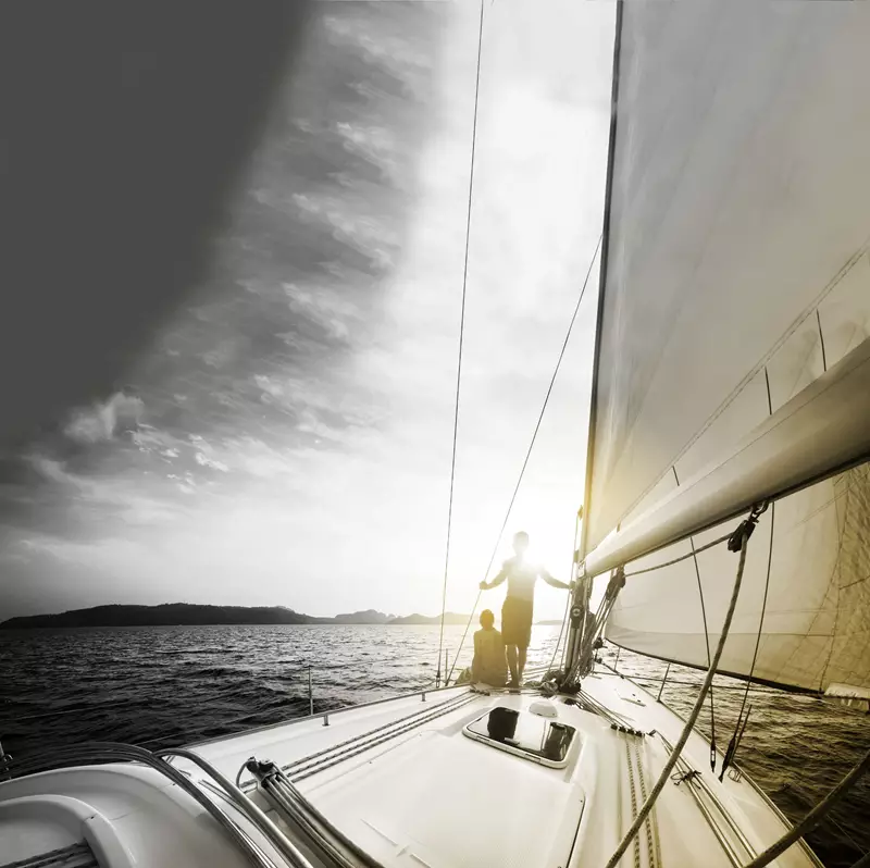 Two people on a yacht with the sun glaring behind them