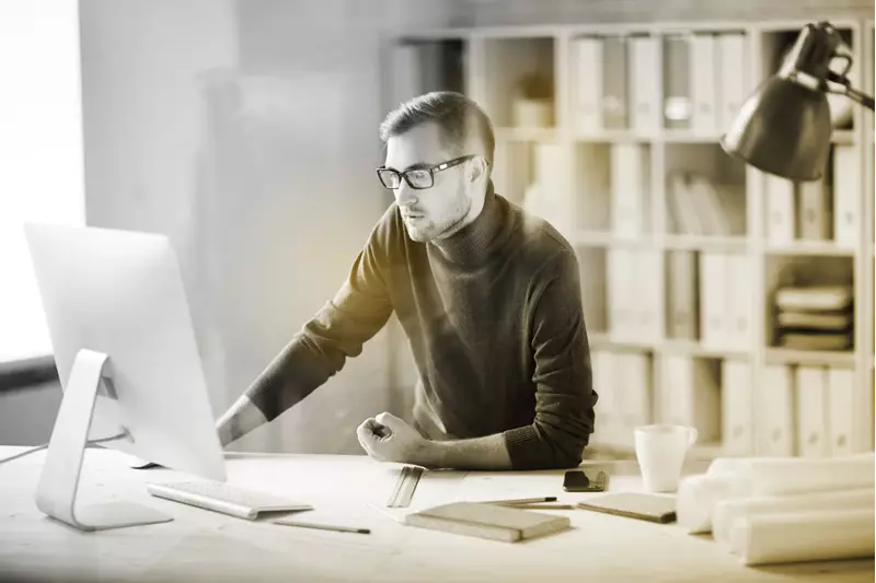 Male wearing eyeglasses working indoors behind a computer