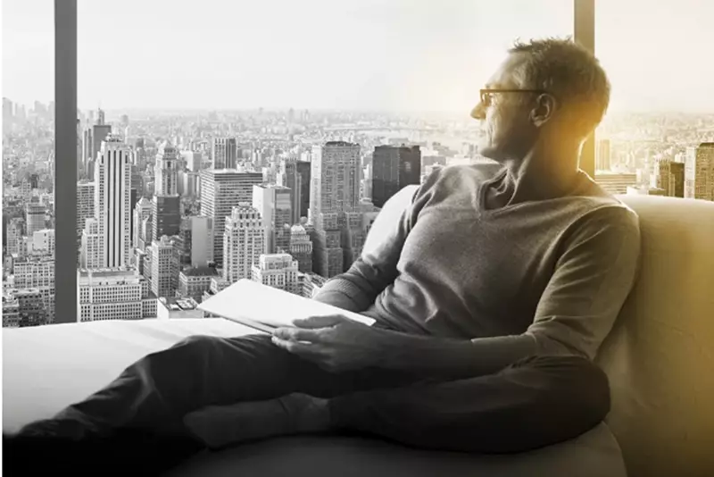 Male wearing eyeglasses holding tablet looking out of window