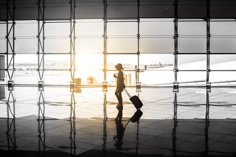 Woman in hat with trolley at airport