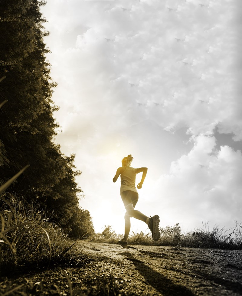 Back view of a female runner running along a path 