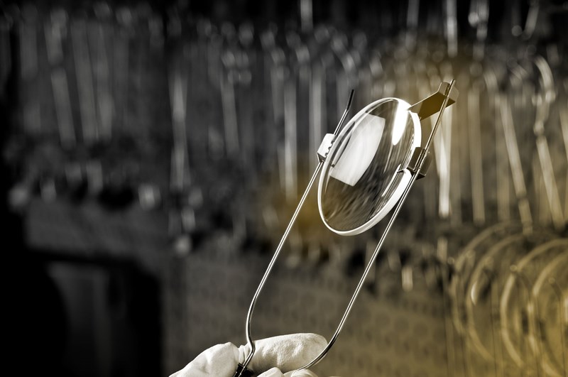 Person holding lens in a clamp for inspection