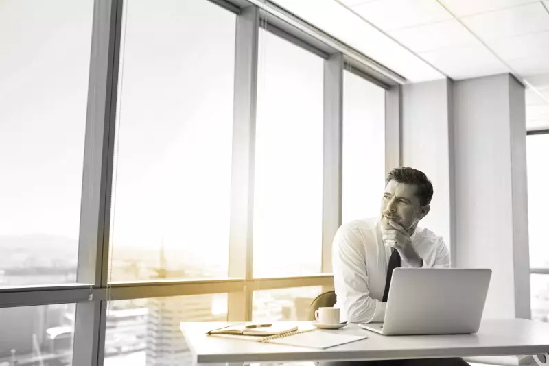 Male sat behind laptop looking out of window