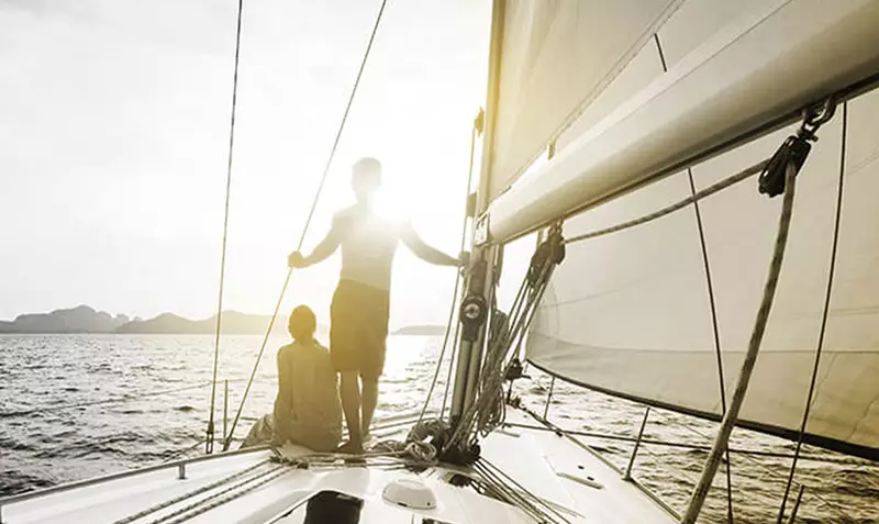 Two people on a yacht with the sun shining over them