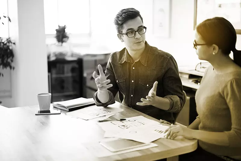 Male speaking to female indoors both wearing eyeglasses