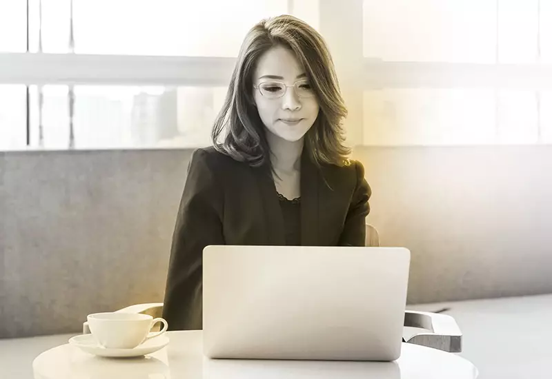 Female wearing glasses sat behind laptop