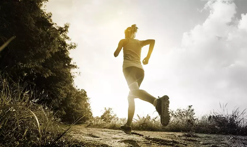 Female runner from behind running along track