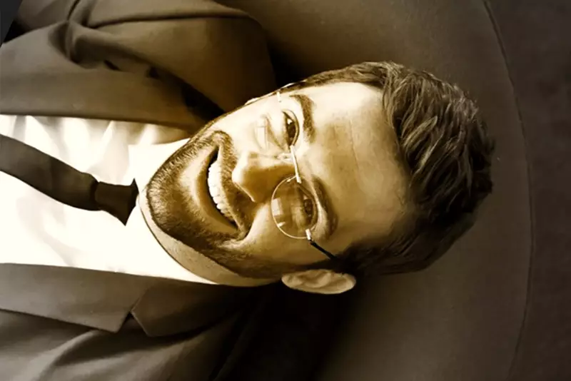 Male wearing glasses lying on chair looking straight at camera