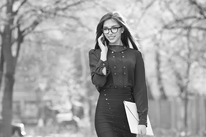 Female walking along park wearing glasses on a phone call